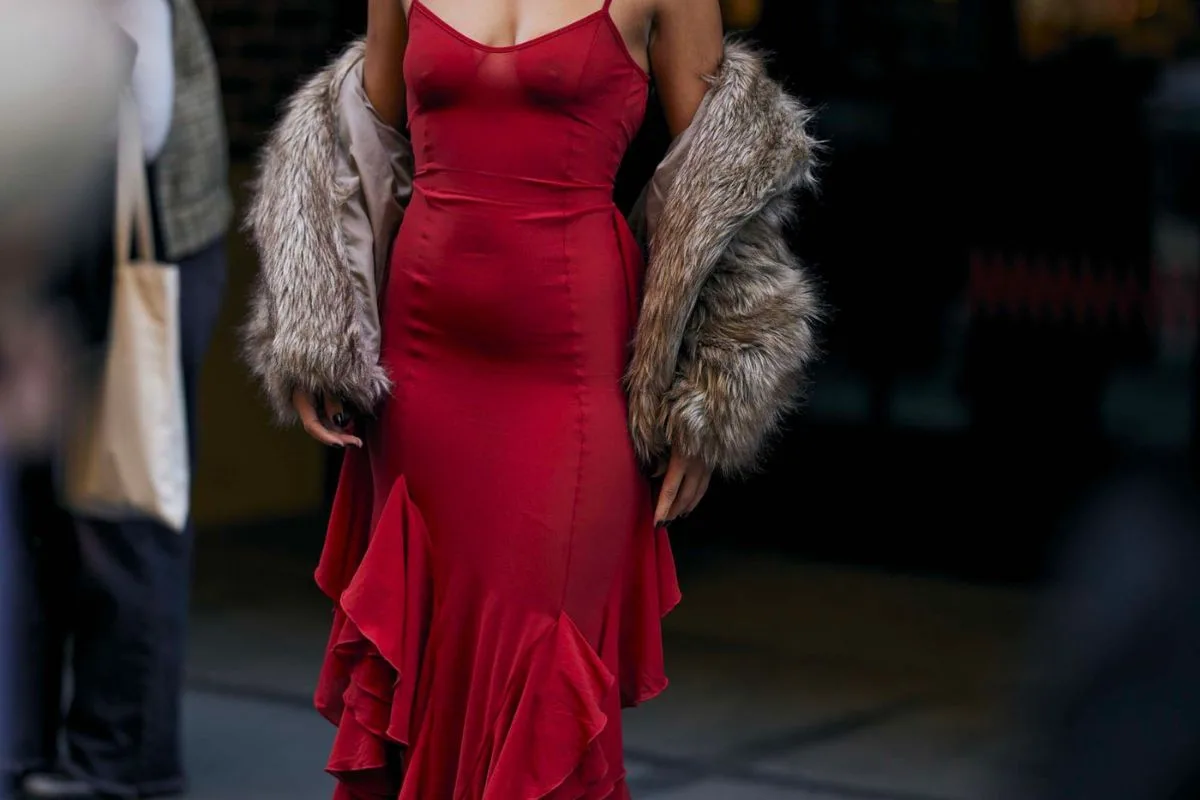 Femme élégante portant une robe rouge avec un manteau en fourrure lors d'un événement en ville.